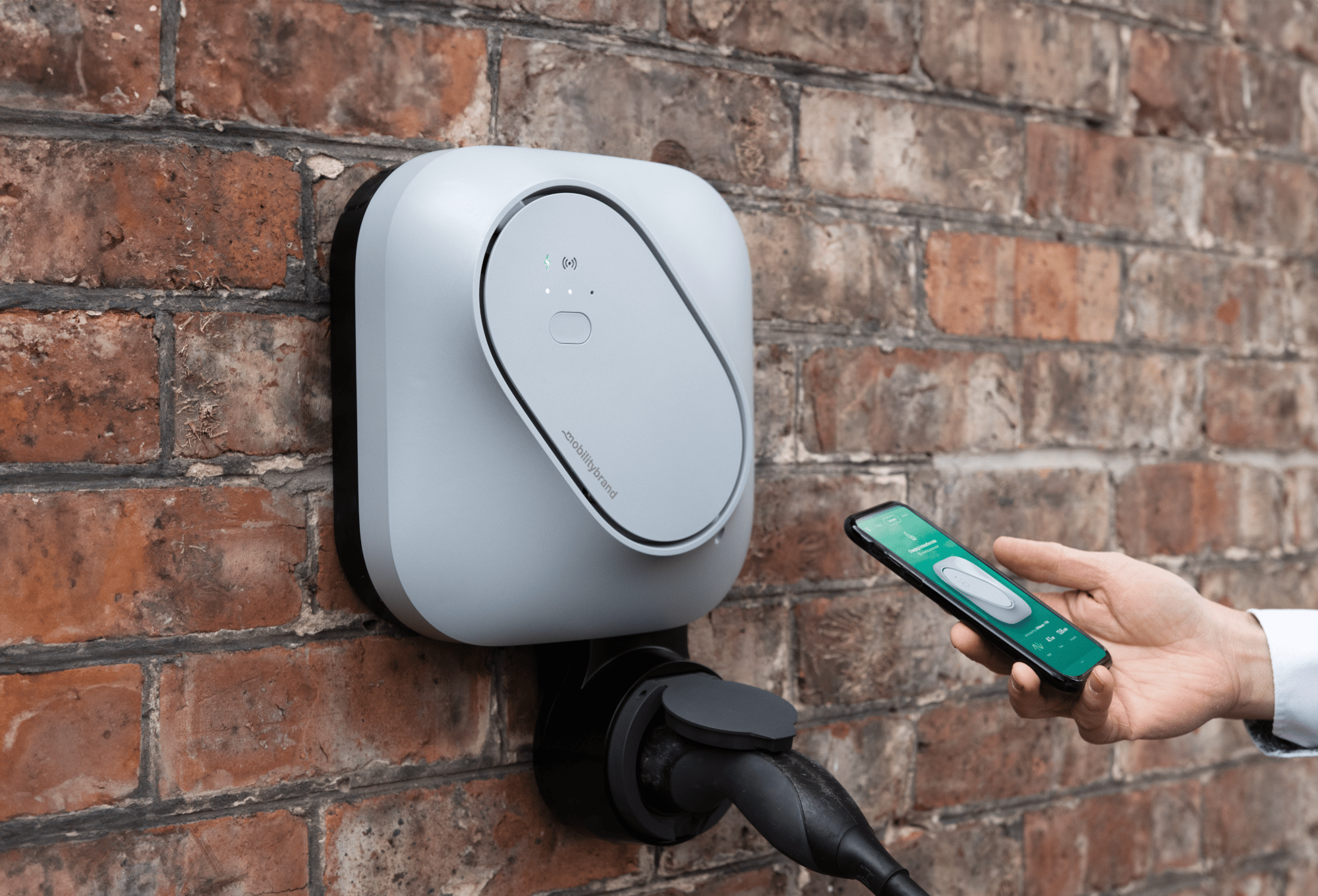Hand holding a phone up to the INCH Core charger on a red brick wall to start a charge