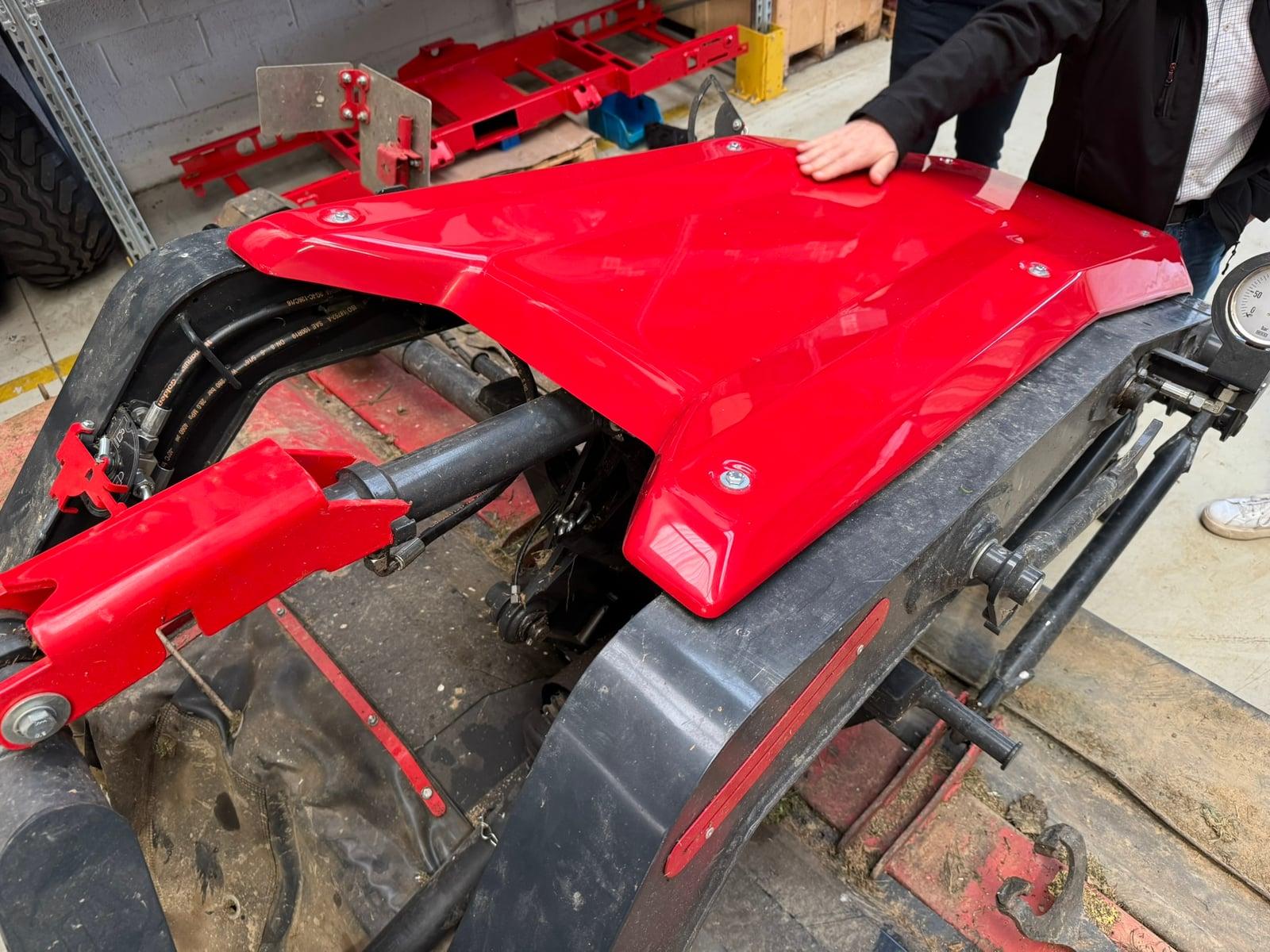 Hand on the red cover of a SIP mower prototype in the workshop