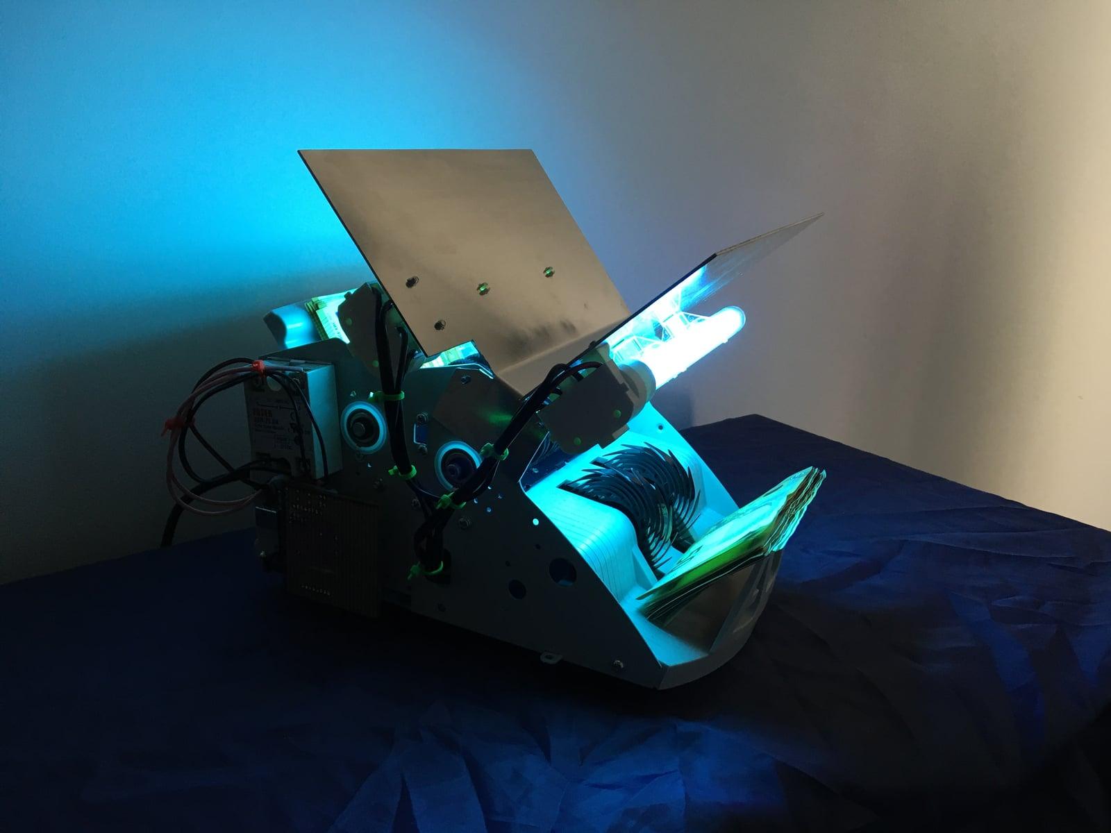 Early Cash Cleaner prototype glowing with blue UV light as banknotes pass through