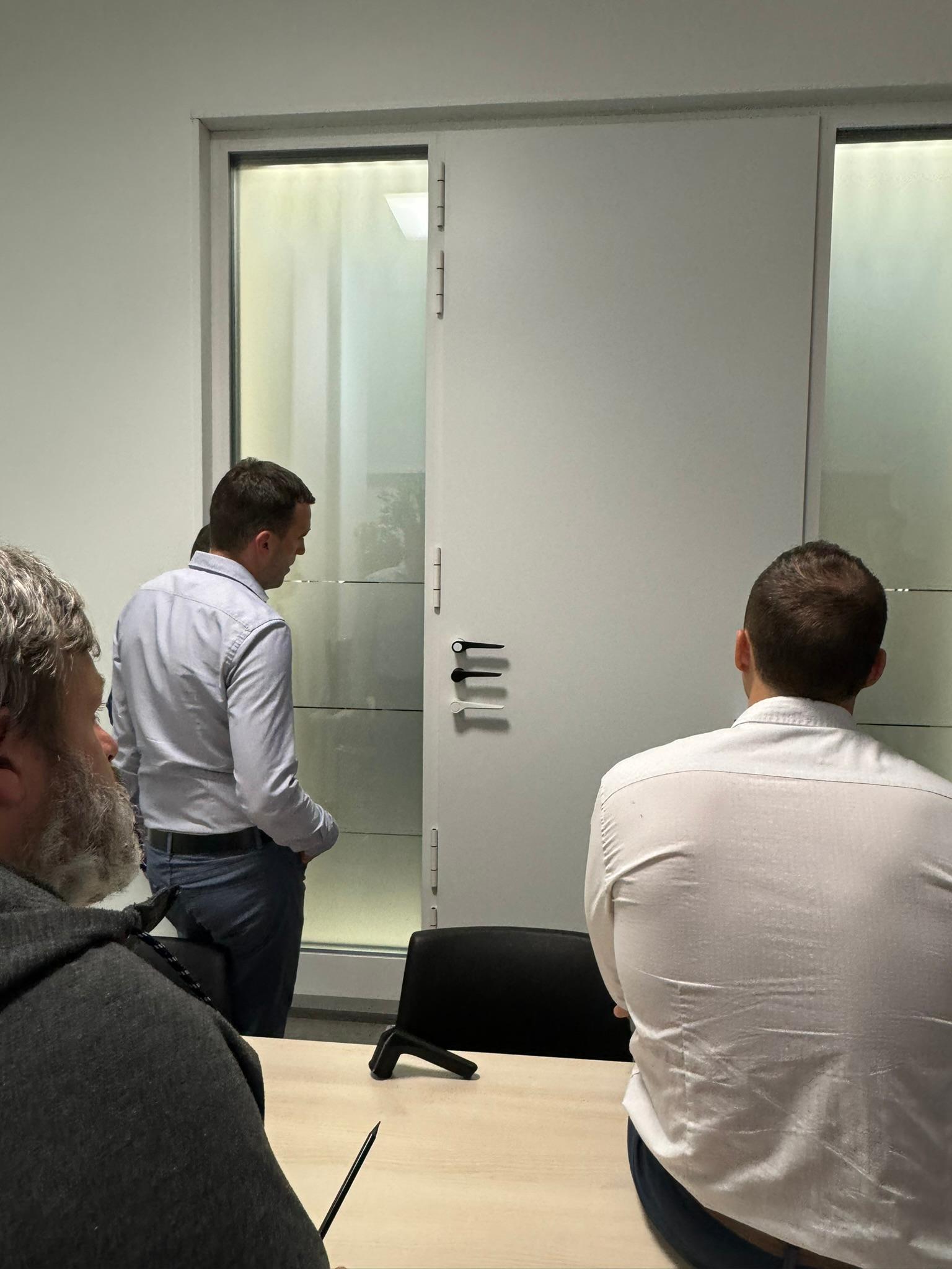 Team reviewing a handle prototype fitted to a door in a meeting room