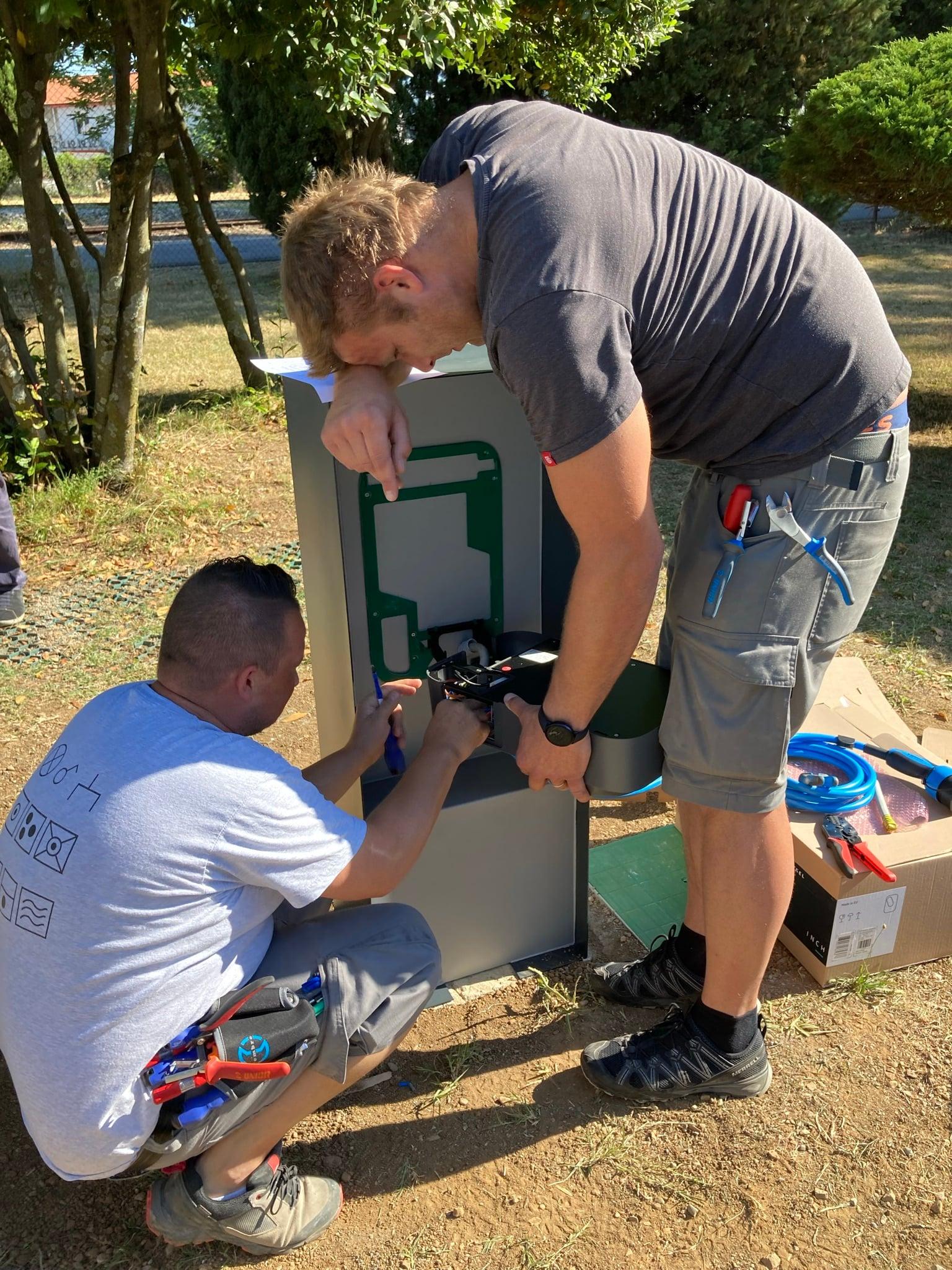 Two installers fitting a charger prototype to an outdoor post
