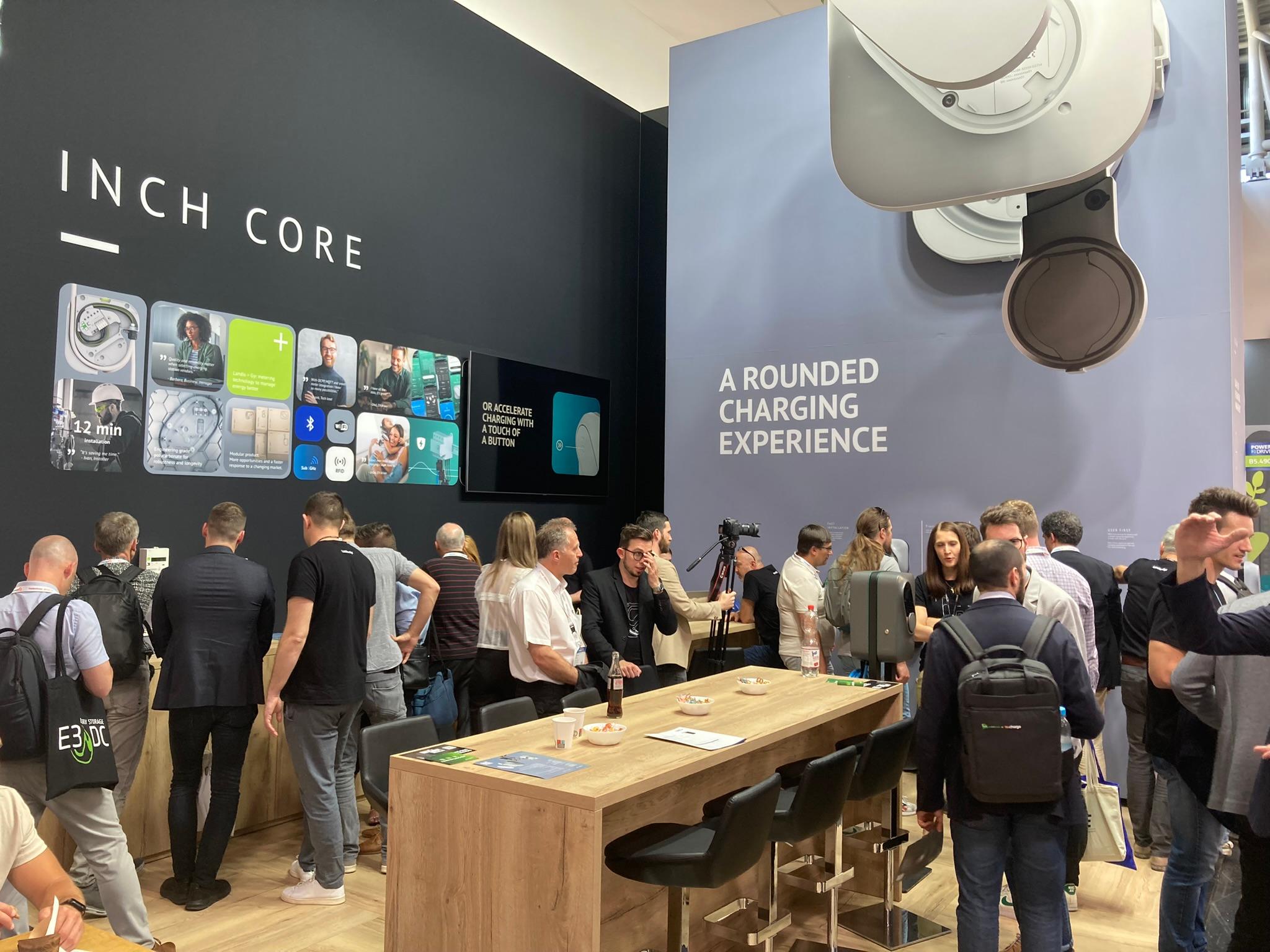 Visitors at the Etrel INCH Core trade-fair stand under the line "A rounded charging experience"