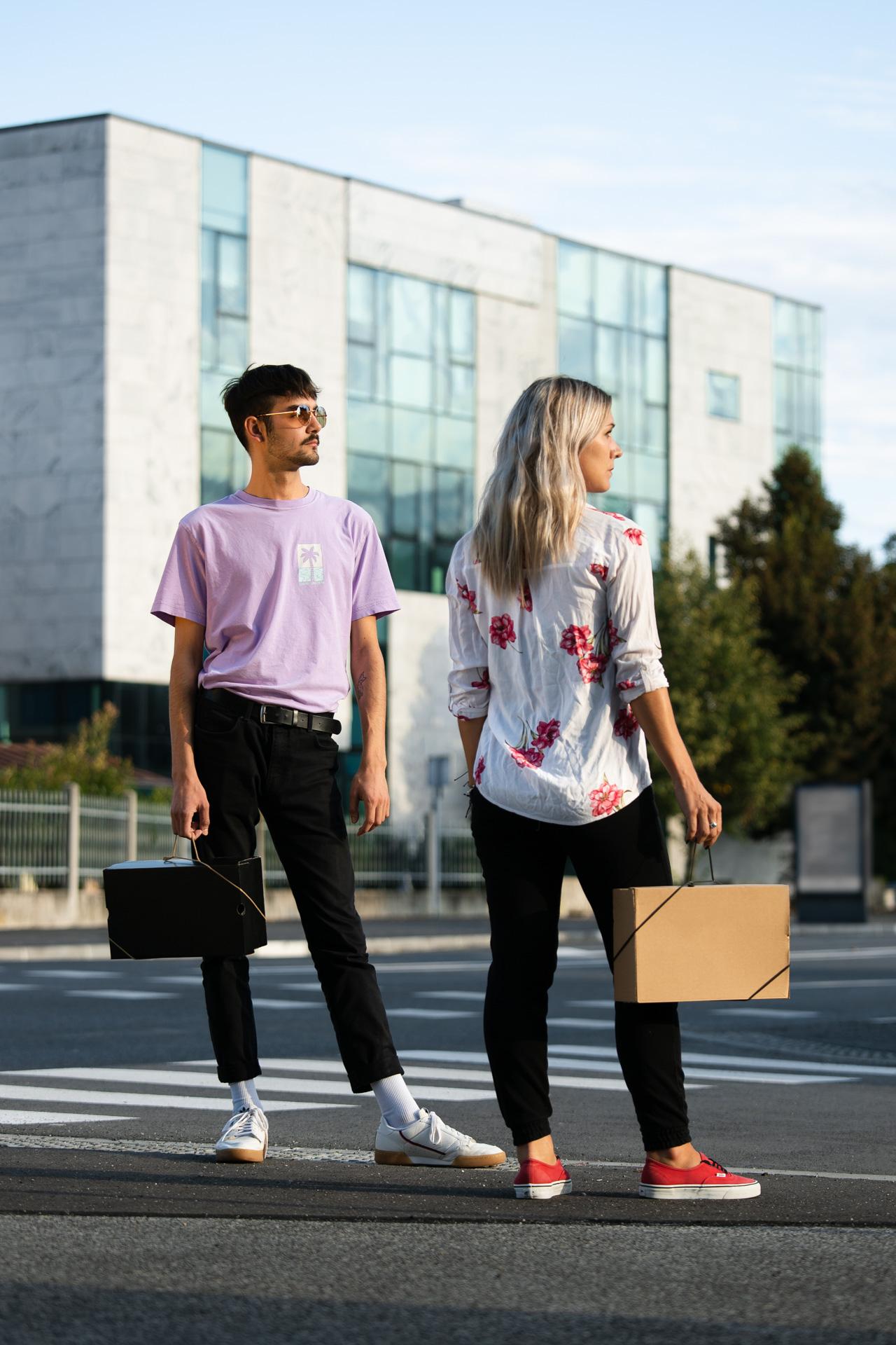 Two people on a street crossing, each carrying a shoebox with a Bagless Cord