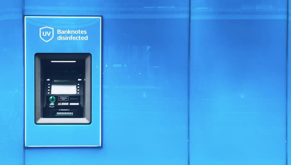 Cash machine set into a blue wall with a "UV Banknotes disinfected" label