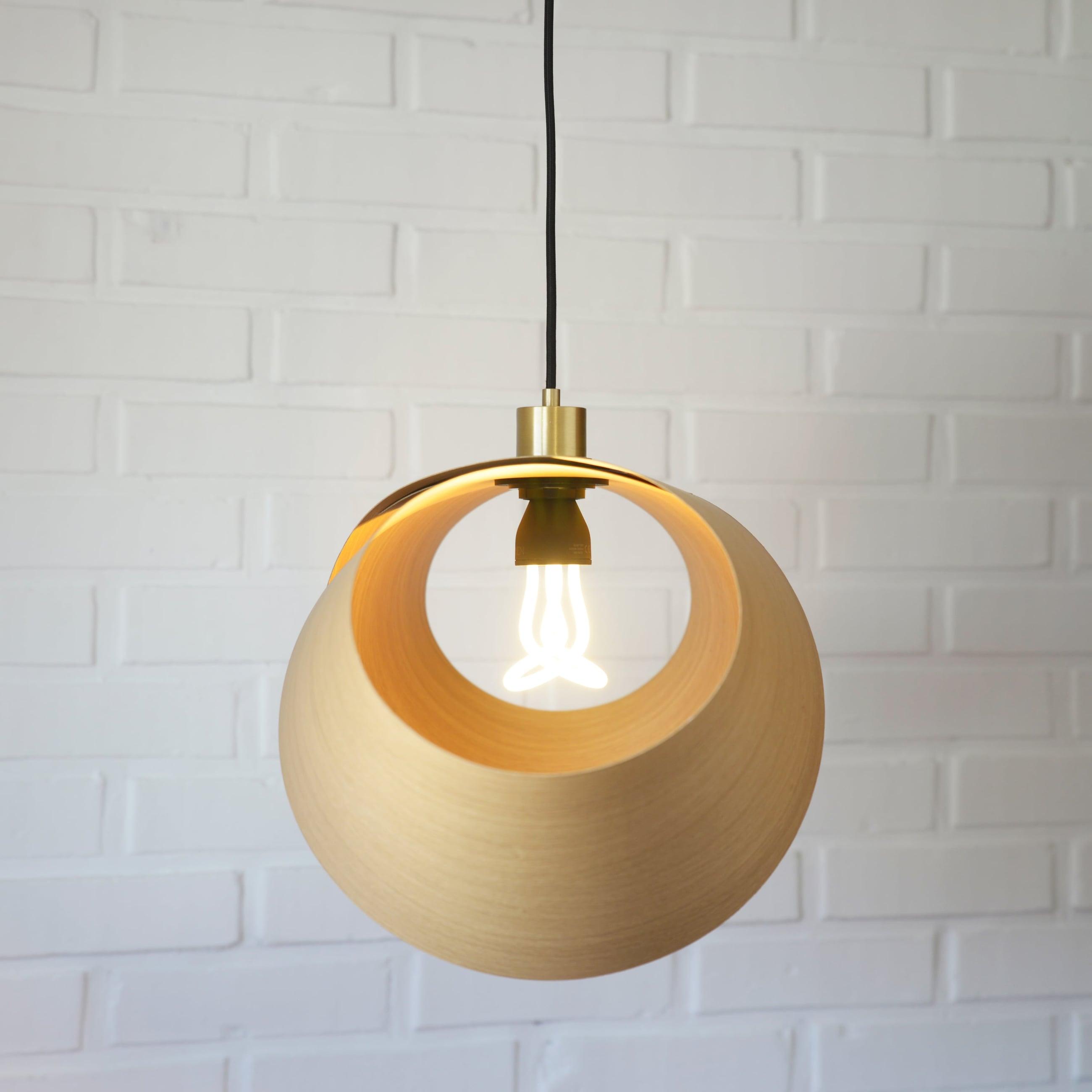 Foldia lamp in oak veneer seen from below, closed, with the lit bulb visible through the opening