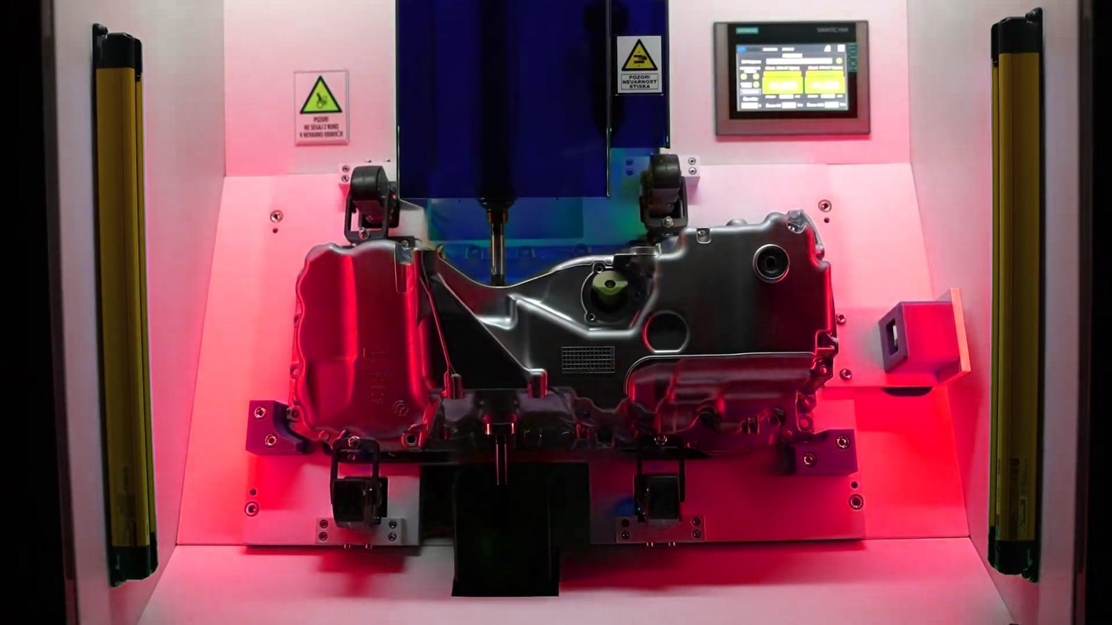 Measurement booth working area lit red with a workpiece clamped in the fixture, signalling a fail